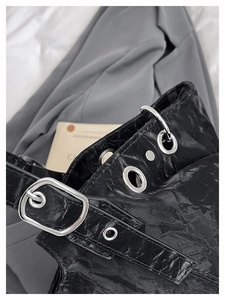 Detail of crinkled black leather bag with large silver eyelets and metal buckle