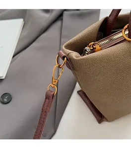 Close-up of golden metal zipper and brown leather trim on canvas tote bag detail