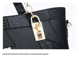 Detail view of black textured leather handbag with gold metal lock and chain strap