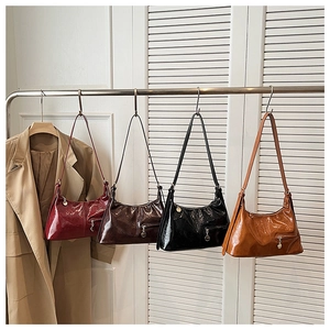 Close-up of stylish glossy tote bags in red, brown, black and orange on a rack