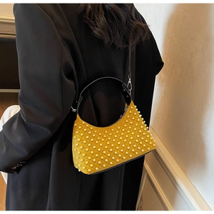 Detail of yellow suede underarm bag featuring dense white pearl studs and black handles