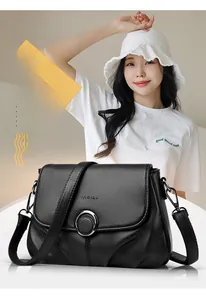 Detail of black pebbled leather crossbody bag with metal magnetic buckle and logo