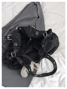Detail of black wrinkled tote bag interior showing silver eyelets and plush charm