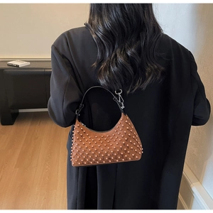 Detail of brown quilted shoulder bag featuring tone-on-tone bead studs and silver hardware