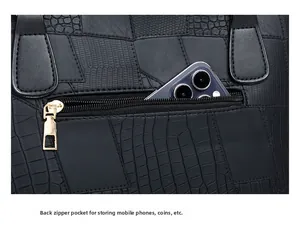 Close-up of the back zipper pocket on black faux crocodile leather bag with phone inside
