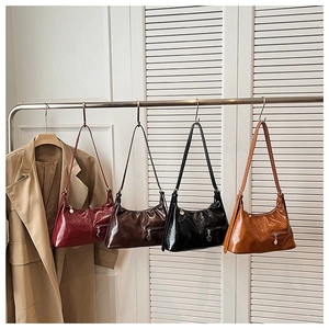 Detail view of four retro hobo bags in assorted colors hanging on a metal rack