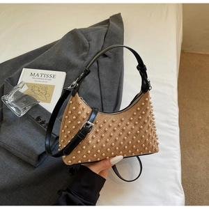 Close-up of camel suede shoulder bag featuring pearl embellishments and black leather strap