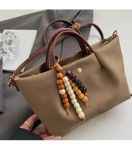 Detail of canvas tote bag with brown leather handles and decorative wood bead tassel charm