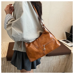 Detail view of glossy brown vintage faux leather shoulder bag with metallic zipper accents