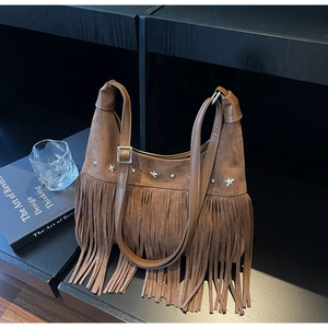 Nahaufnahme der braunen Wildledertasche mit silbernen Sternnieten und langen Fransen