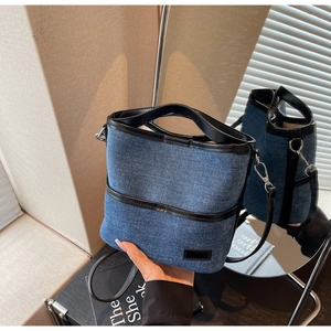 Detailansicht einer blauen Denim-Beuteltasche mit schwarzen Lederbesätzen und Gurt