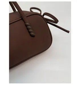 Gros plan du sac marron foncé mat avec texture de tissu et vis décorative à logo