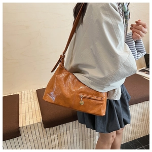 Detail of vintage caramel brown pleated leather shoulder bag with metallic pendant zip
