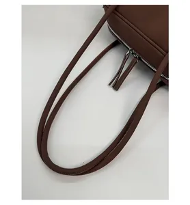 Détail de la poignée en cuir marron mat avec fermeture éclair argentée et couture