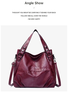 Detailed view of burgundy faux leather handbag with cross-stitch pattern and silver hardware
