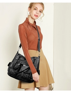 Detail of black washed leather biker bag with silver zippers and multi-pocket design