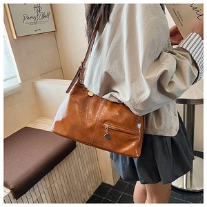 Detail of caramel pleated leather texture and metal pendant zipper pocket on hobo bag