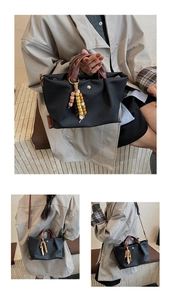 Detail of black canvas bag featuring colorful beaded tassel and leather texture handles