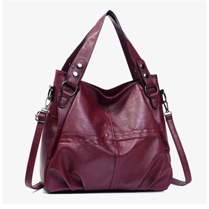 Detail view of wine red PU leather tote bag with cross-stitched texture and dark hardware