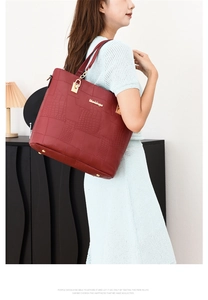 Detail of red crocodile pattern tote bag with gold logo and adjustable shoulder strap