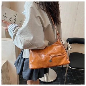 Detailed view of caramel oil-waxed leather shoulder bag styled on a female model