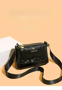 Detail of black Boston bag with snakeskin embossing, gold hardware and wide strap