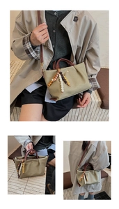 Detailed view of green tote bag with brown straps and colorful ethnic bead charm