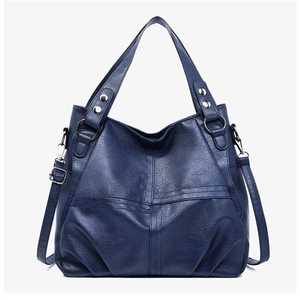 Detail of dark blue hobo tote bag showing pebbled leather texture and silver rivets