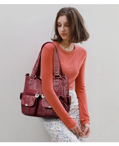 Macro shot of burgundy vintage leather shoulder bag with decorative metal rivets