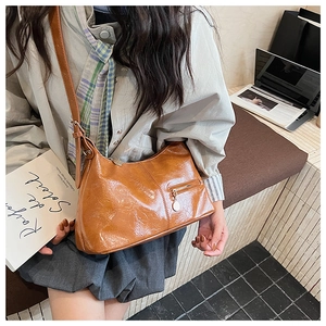 Detail of vintage brown crossbody bag with oily leather texture and metal ring zipper