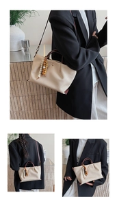 Detail view of cream canvas tote bag with leather straps and decorative bead charm