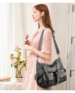 Detail of dark gray soft leather tote bag with functional pockets and adjustable strap