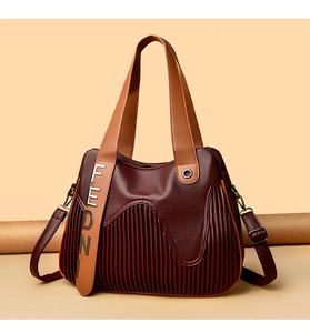Détail d'un sac à main bordeaux en cuir grainé avec design plissé et accents métal