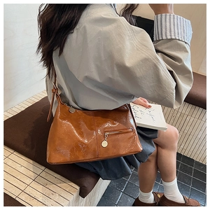 Detail of vintage brown oil wax leather shoulder bag with glossy texture and metal charm