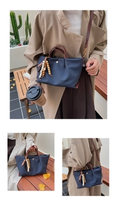 Detail of navy canvas bag with brown leather handles and colorful beaded tassel detail