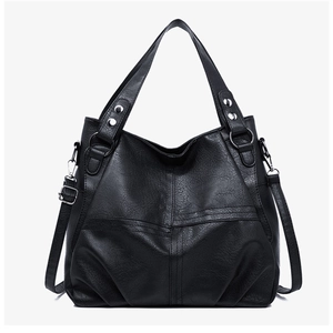 Detail of black pebbled faux leather tote featuring cross stitching and silver hardware