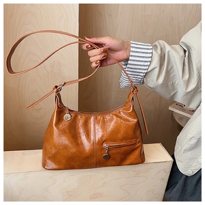 Detail view of caramel faux leather bag featuring natural wrinkles and a metal zipper pull