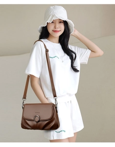 Close-up of dark brown pebble leather crossbody bag with silver ring buckle and adjustable strap