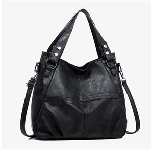Detail of black pebbled PU leather tote bag with silver hardware and detachable strap