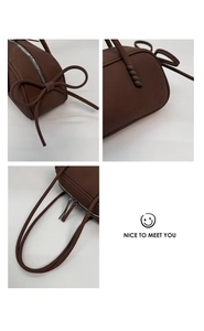 Détails d'un sac porté épaule marron avec nœud décoratif et fermeture éclair argent