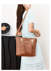 Brown crocodile texture handbag with adjustable strap shown on model's shoulder