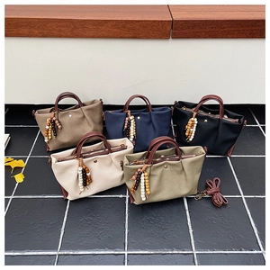 Close-up of minimalist canvas handbags with leather handles and decorative beaded charms