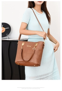 Detail of brown crocodile pattern patchwork shoulder bag with gold chain and logo
