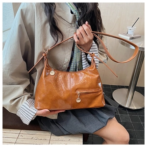 Detail of caramel brown wrinkled PU leather bag with gold hardware and front zipper pocket