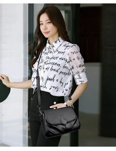 Detail of soft black lychee grain leather handbag featuring metal round buckle and flap