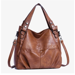 Detail view of brown PU leather tote with metal rivets and adjustable shoulder strap