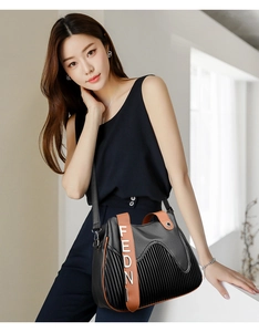 Détail du sac cabas en cuir plissé noir avec anses brunes et accents métalliques
