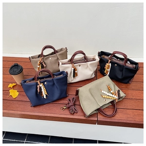 Detailed arrangement of canvas handbags with leather handles and ethnic bead charms