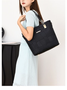 Close-up of black tote bag with croc-embossed texture and gold-tone metal padlock detail