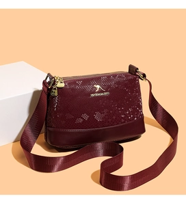 Detail of burgundy Boston bag showing snakeskin texture and golden kangaroo logo